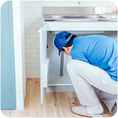 洗面台下排水管を調べる修理スタッフの写真