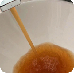 水道管から出る赤く濁った水の写真