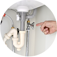 洗面所の止水栓を指差す修理スタッフの写真